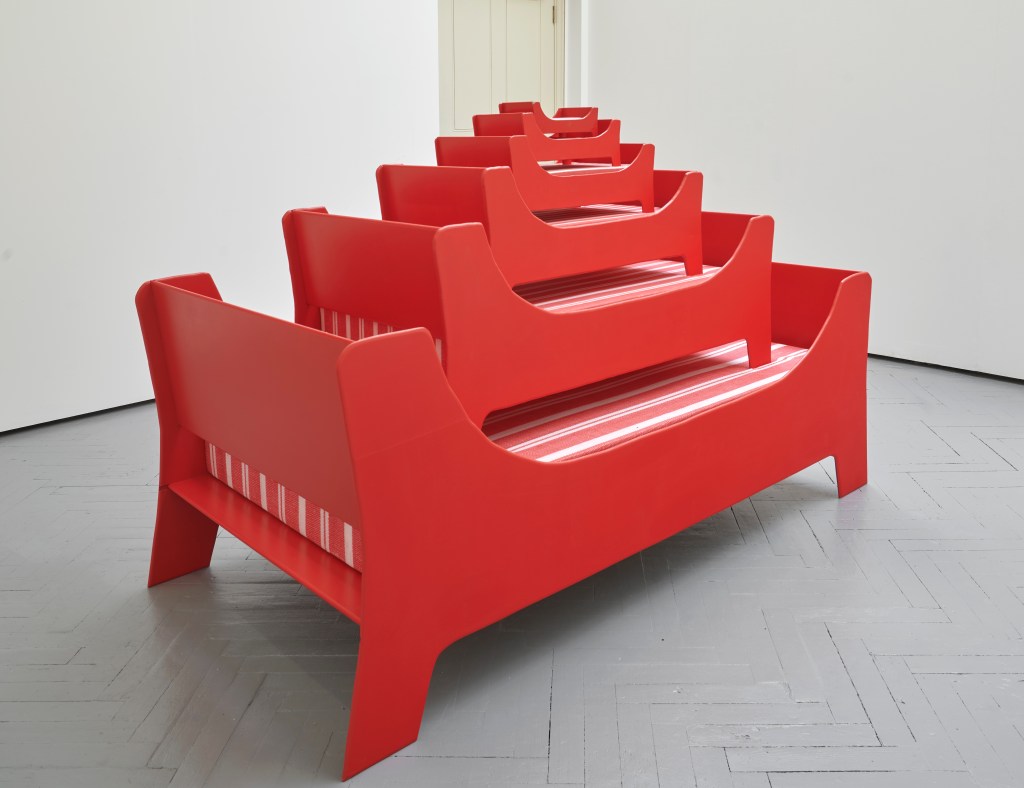 Bed (2025) by Esther Gamsu, made of MDF, paint, glue, printed cotton, and foam. The work resembles a handcrafted, upholstered structure combining sculptural form and domestic materials.