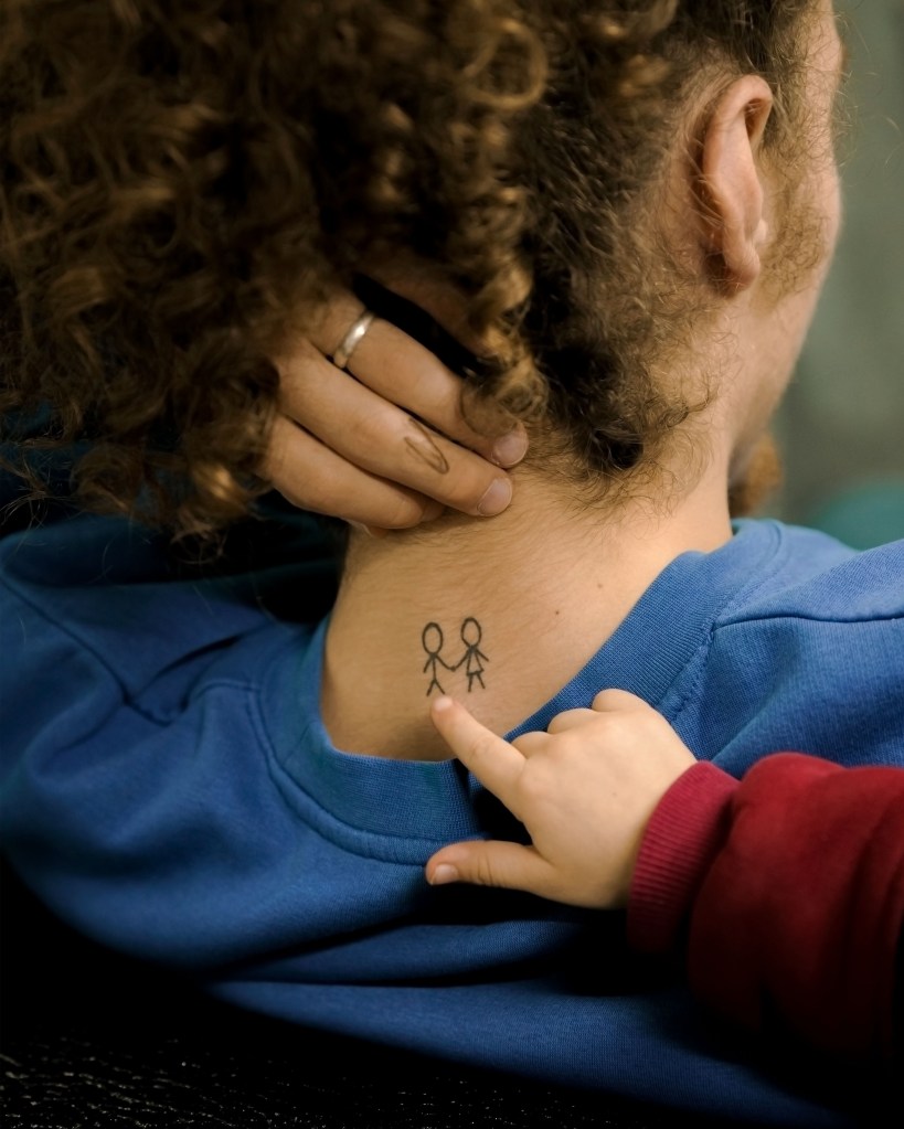 Close-up of a young woman pointing at her brother’s tattoo, dedicated to Irene, in Gaziantep, Turkey. Photo by Carola Cappellari, 2022.