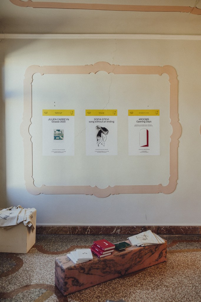 A cozy exhibition setting with books, posters, and soft natural light, capturing the presentation of Libreria delle Api in Venice