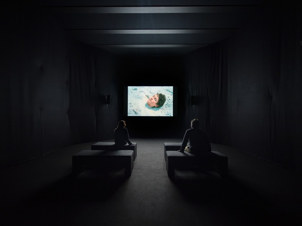 Installation view of Stendhal Syndrome (2024) by Nan Goldin, showing moving images projected within a minimal, dark exhibition setting at Pirelli HangarBicocca, Milan. Photo by Agostino Osio