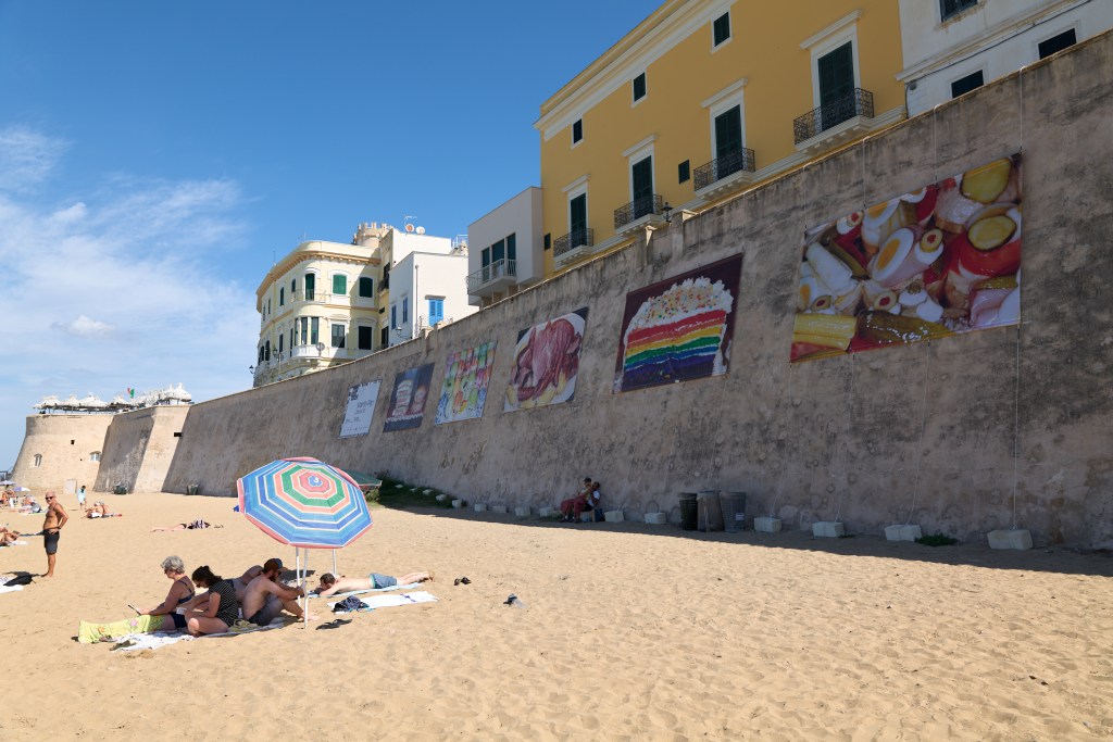 Outdoor installation view of Snack It! by Martin Parr on Spiaggia della Purità, Gallipoli, as part of Yeast Photo Festival 2025. Photo by Florian W. Mueller