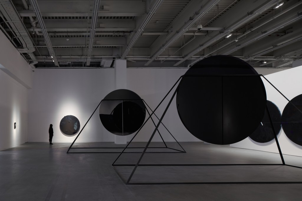 Wide view of an exhibition space at the 13th Shanghai Biennale showing Torkwase Dyson’s large-scale abstract artworks arranged within an architectural installation, emphasizing geometry, dark surfaces, and spatial tension.