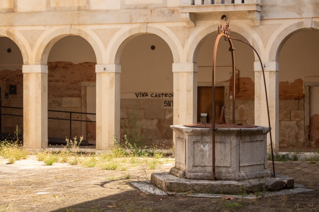 The cloister of the former infirmary, with a covered walkway surrounding an open courtyard and visible architectural details