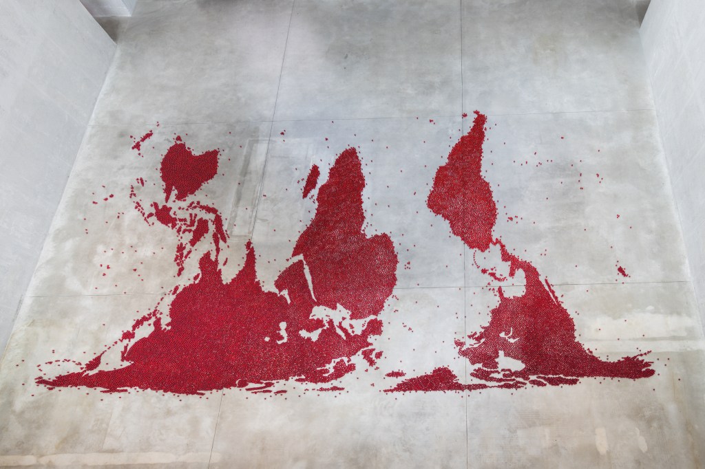 Installation view of Mona Hatoum’s Map (red) (2026), composed of numerous small red glass spheres arranged across the floor to form a map-like configuration