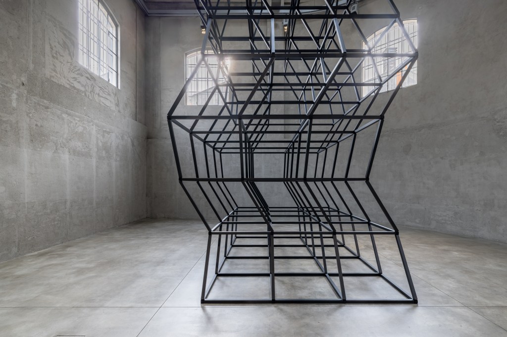 Installation view of Mona Hatoum’s All of a Quiver (2022), a kinetic structure of metal elements activated by a motor within the gallery space.
