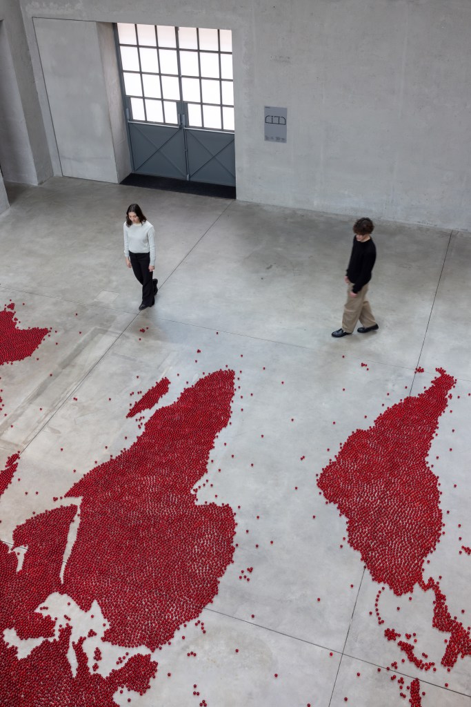 Installation view of Mona Hatoum’s Map (red) (2026), composed of numerous small red glass spheres arranged across the floor to form a map-like configuration