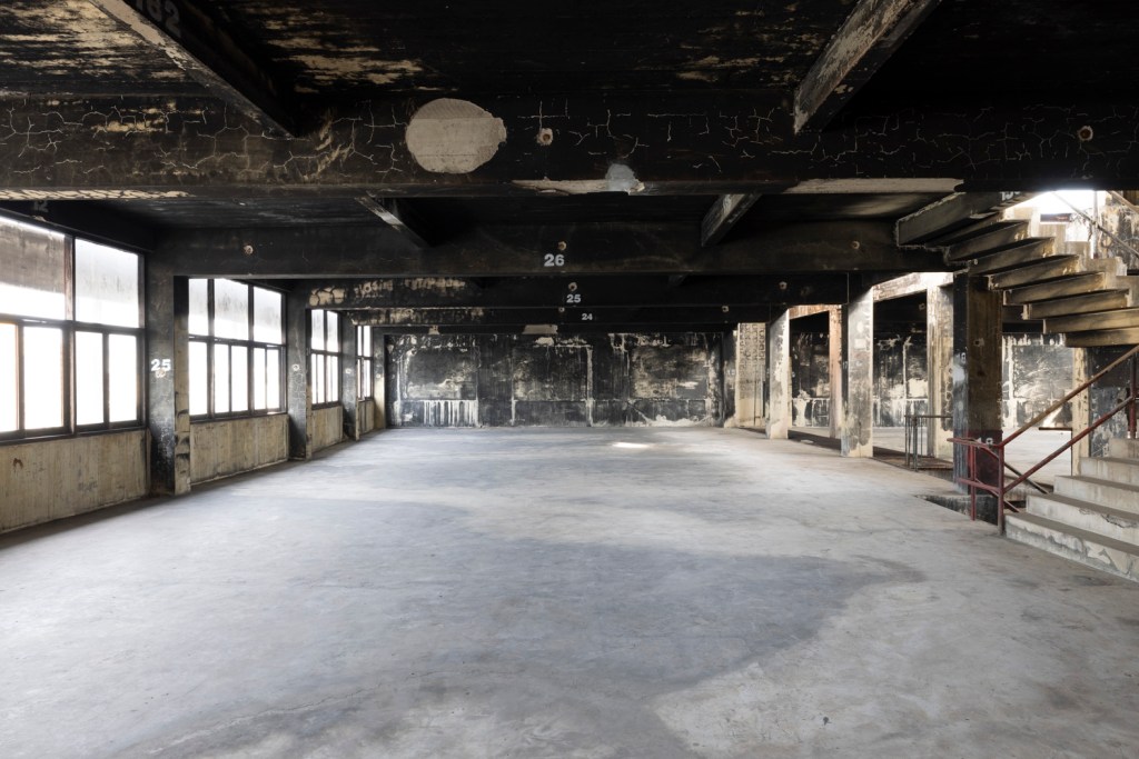 Interior of Bangkok Kunsthalle featuring raw industrial architecture with exposed brick, concrete surfaces, and open exhibition spaces