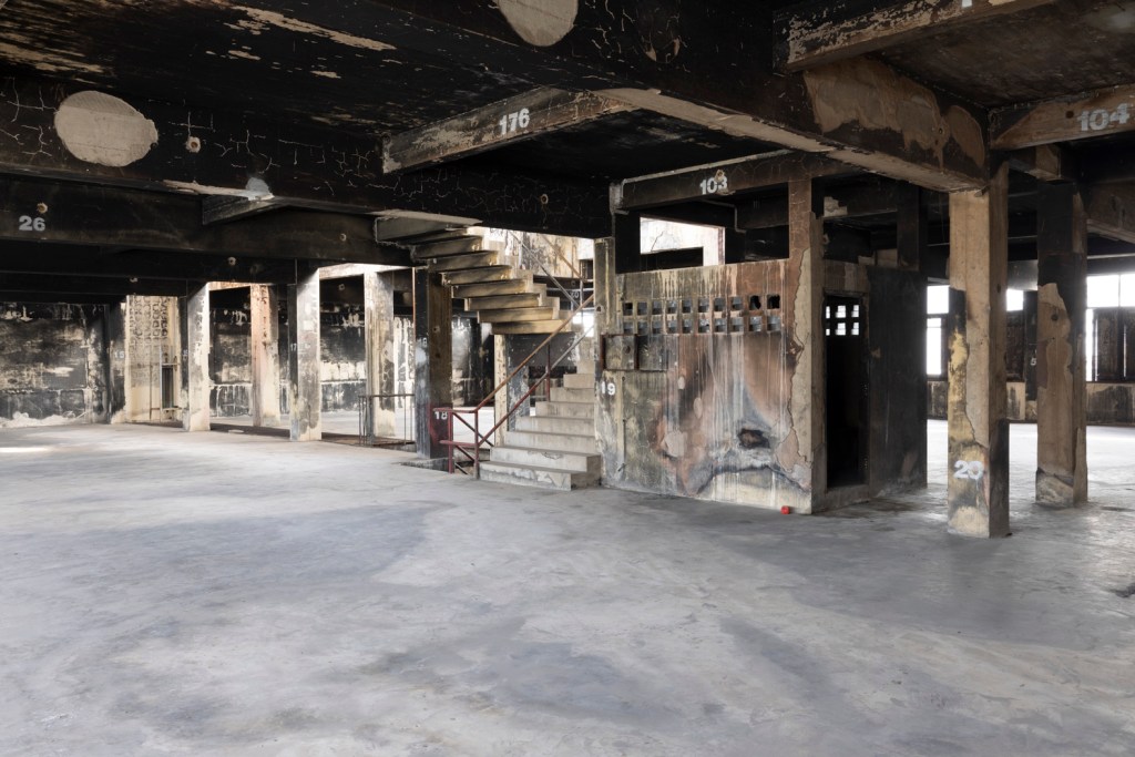 Interior of Bangkok Kunsthalle featuring raw industrial architecture with exposed brick, concrete surfaces, and open exhibition spaces