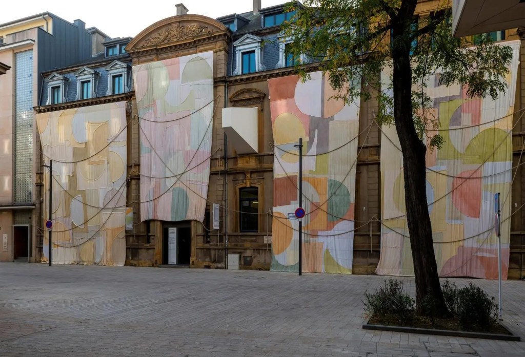 Installation view of Adrien Vescovi's Jours de lenteur at Casino Luxembourg, featuring fabric-based works displayed throughout the exhibition space.