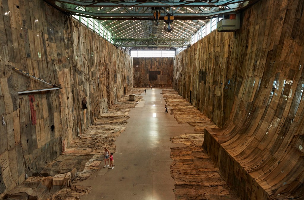 Installation view of Ibrahim Mahama’s No Friend but the Mountains 2012–2020 (2020) at the 22nd Biennale of Sydney on Cockatoo Island. The work consists of charcoal jute sacks, metal tags, scrap metal and tarpaulin arranged across the site