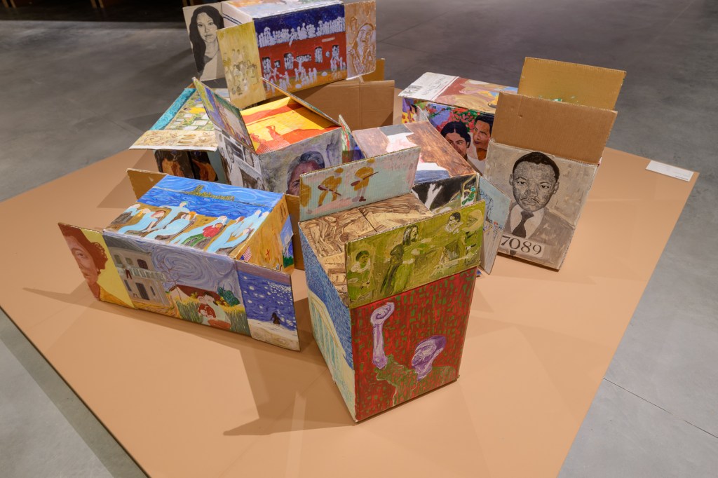 Sohrab Hura, Timelines, 2024. Nine small acrylic-and-gesso paintings on corrugated cardboard boxes, depicting Bees, Delhi, Mail, Mother, Protest, Sheila, The Bus, The Olive Tree, and The School. Each work measures 35 × 30 cm. Presented in the 61st International Art Exhibition – La Biennale di Venezia, In Minor Keys. Photo by Andrea Avezzù. Courtesy of La Biennale di Venezia.